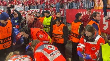 Sanitäter kümmern sich um einen verletzten Fotografen vor der Südkurve