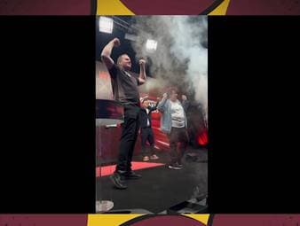 SPORT1-Kommentator Basti Schwele tanzt beim Walk-On von Dirk van Duijvenbode mit einem Darts-Fan und dem Niederländer auf der Bühne.