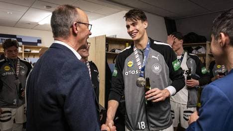 Bundeskanzler Friedrich Merz (l.) besucht die deutschen Handballer in der Kabine